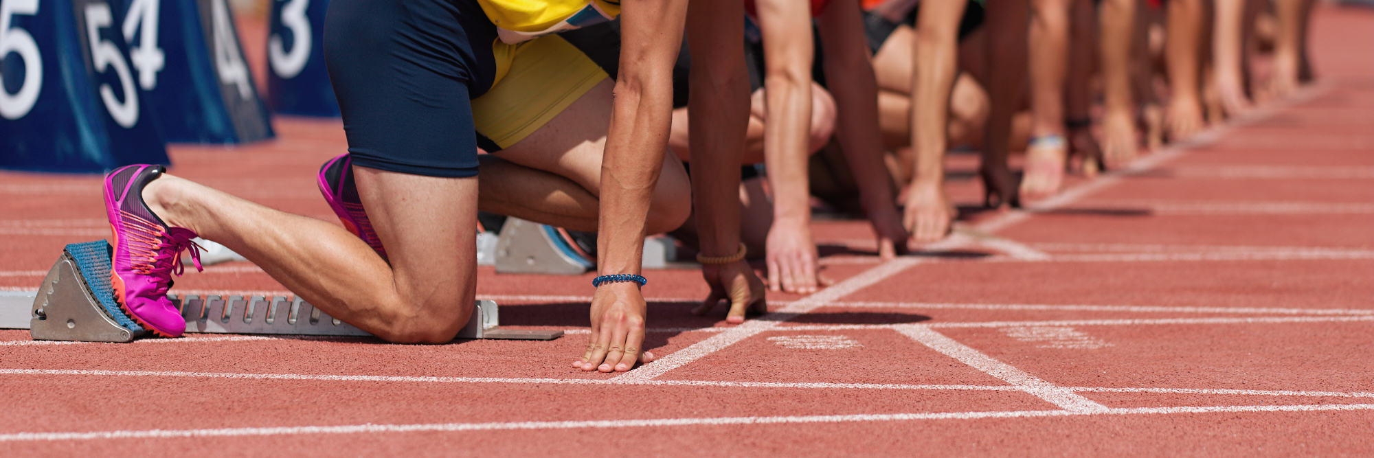 Group of male track athletes on starting blocks.Hands on the starting line.Athletes at the sprint start line in track and field