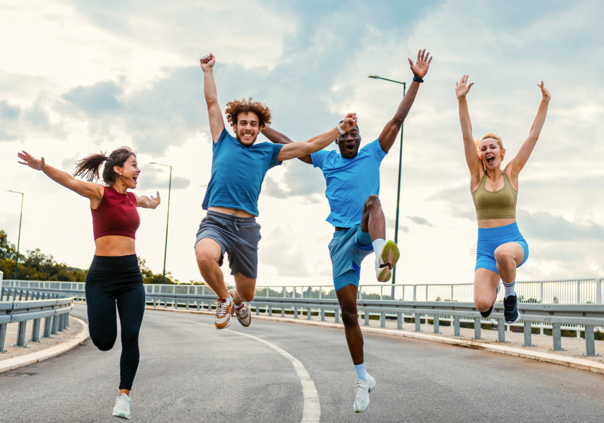 Excited group of people running and jumping together on outdoor road.
