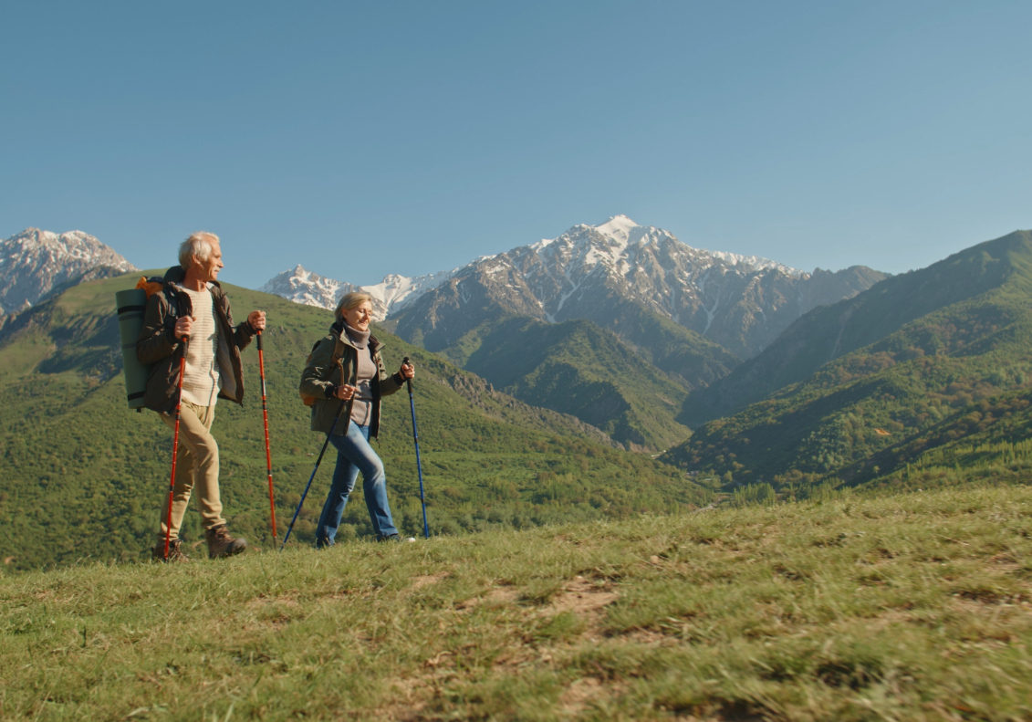 Mature caucasian couple on vacation, having a hike in spring mountains, spending time together after retirement together travelling - tourism, pension concept